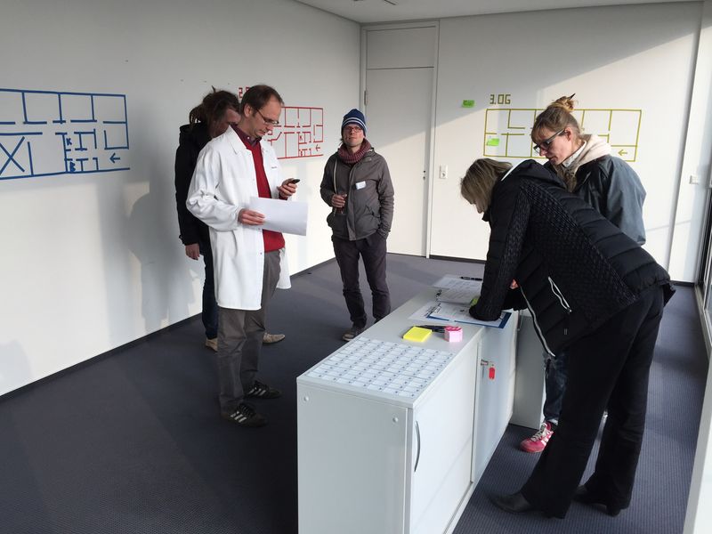 Besucher beugen sich bei einem Rundgang über Pläne an einem Tisch